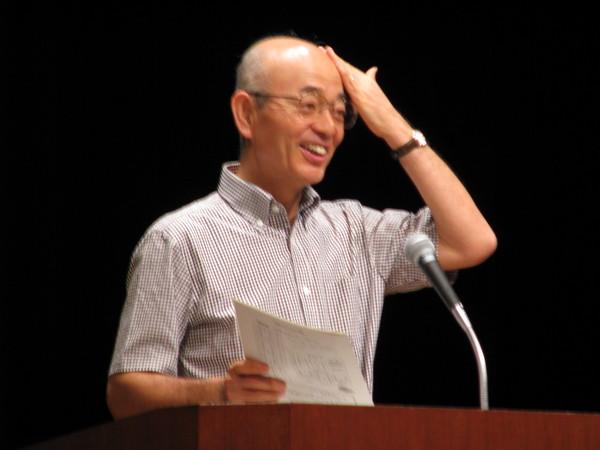 マイクの前でおでこをおさえて笑っている市長の写真